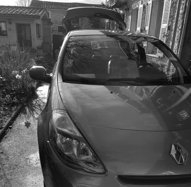 Renault Clio grise après un lavage extérieur à la main, capot et phare avant brillants